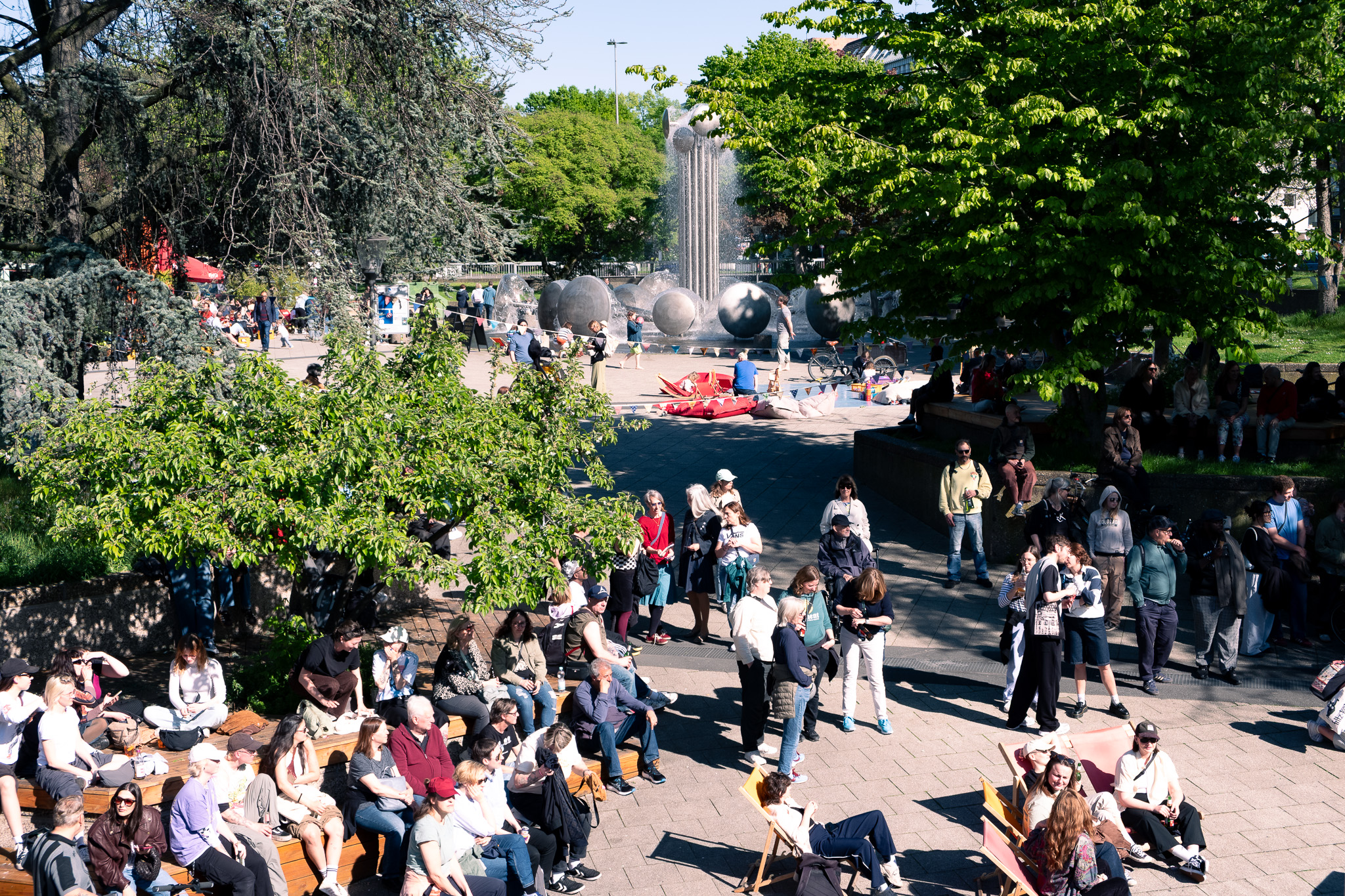 Menschen sitzen im Abendlicht am Brunnen des Ebertplatzes.